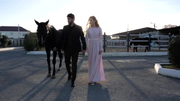 Casal apaixonado caminha com cavalo na pista de corrida câmera lenta — Vídeo de Stock