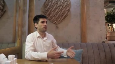 rahat gömlek duygusal koyu saçlı adam restoranda kanepede işaret jest ile garson çağırır