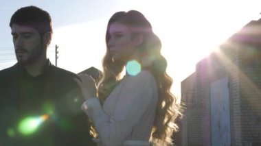 Genç sarışın kadın, erkeğin omuzlarını ağır çekimde tutuyor.