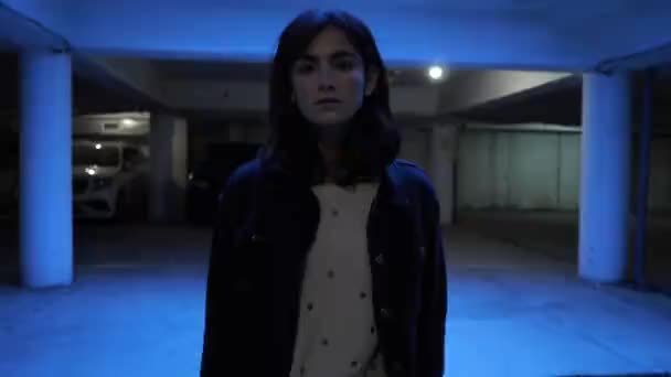 在蓝色电灯下 漂亮的黑发女子站在地下停车场 挡住汽车慢动作 — 图库视频影像
