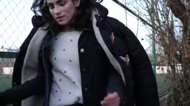 moda esmer yeşil çim yavaş hareket ile stadyum karşı metal siklon çit ve ağaçların yakınında yürüyor