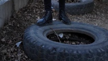 siyah ayakkabı ve pantolon şık kız kahverengi çim yavaş hareket yakın görünümü arasında eski terk edilmiş lastik üzerinde yürüyor