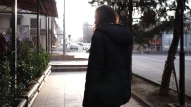 siyah pansuman moda kız ağaçlar yavaş hareket ile şehir caddesinde kaldırımyeşil bitki pot kenarı üzerinde oturur