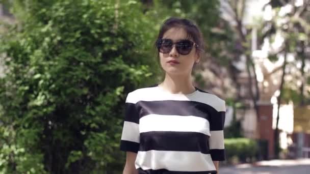 Woman with big sunglasses and in striped dress walks slowly — Stock Video