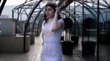 kısa kıvırcık koyu saçlı kız ve taç elbise duruyor