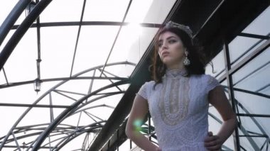 Kadın elleri beyaz elbiseli ve tacı olan kalçalarında poz veriyor.