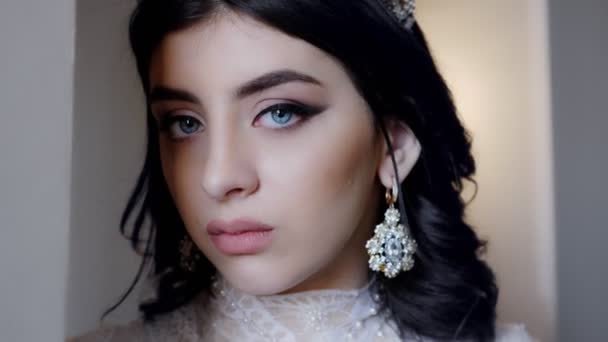 Belle femme aux yeux bleus et maquillage se tient en robe blanche — Video