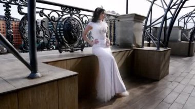 beyaz gelinlik bayan kahverengi ahşap parapet oturur