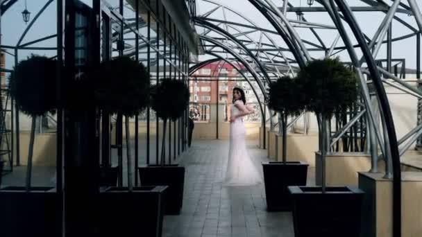 Modelo agradable posa en vestido largo de pie en la terraza de cristal — Vídeo de stock