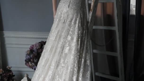 Πανέμορφη νύφη σε φόρεμα με χάντρες στέκεται σε λευκή σκάλα — Αρχείο Βίντεο