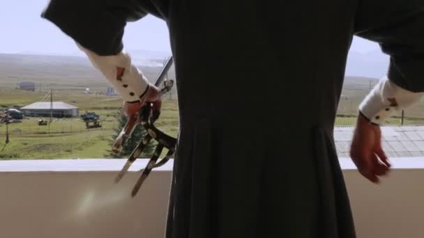 Człowiek w czerkieski stawia na sztylet skórzany pasek na balkonie — Wideo stockowe