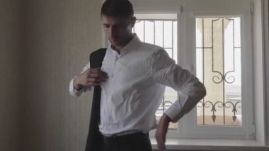 koyu saçlı adam pencereye karşı gömlek yelek koyar