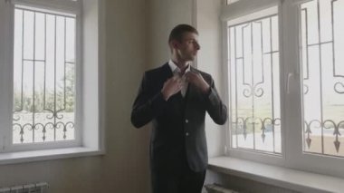 takım elbiseli ciddi genç adam beyaz gömlek yaka düzeltir