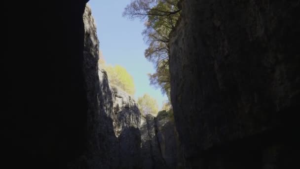 Höga klippor av mörk sten klyfta med blå himmel remsa och träd — Stockvideo