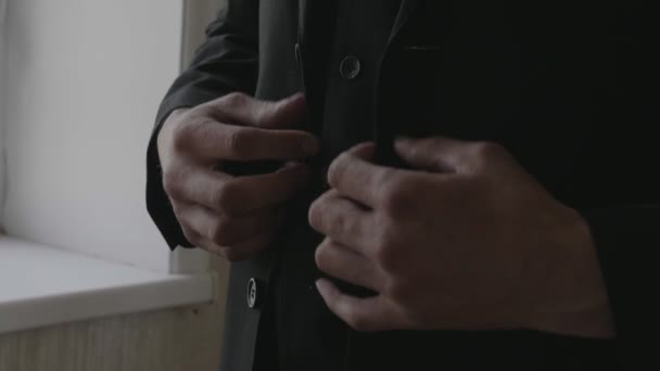 Homem próximo fica na sala espaçosa prende botões na jaqueta — Vídeo de Stock