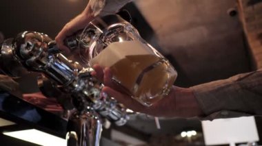 deneyimli barmen bar musluklar düşük açı çekim yakın çekim yavaş hareket ile cam kadeh içine sarı köpüklü bira döker