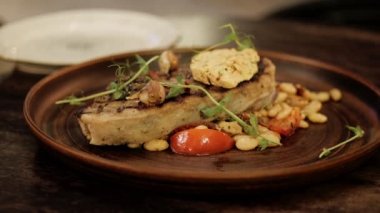 ahşap masa üzerinde kahverengi tabakta et çekirdekleri ve domates ile lezzetli yemek yakın yuvarlak yavaş hareket