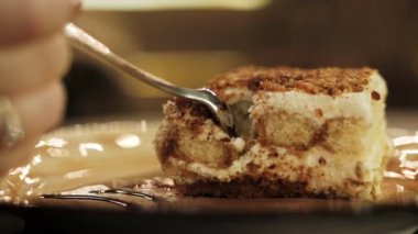 gümüş kaşık yakın görünümü yavaş hareket ile kahverengi plaka üzerinde altın yüzük dilimleri pasta ile restoran ziyaretçi el