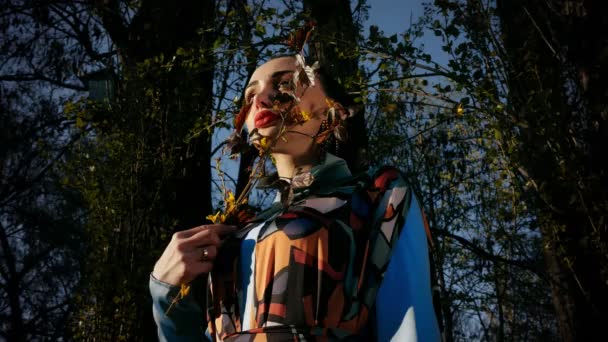 드레스의 화려한 여성은 슬로우 모션에서 가지와 나무에 — 비디오