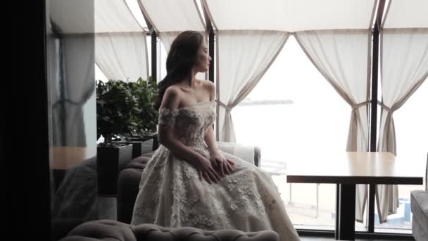 美丽的女人在白色优雅的礼服坐在餐厅的餐桌上 — 图库视频影像