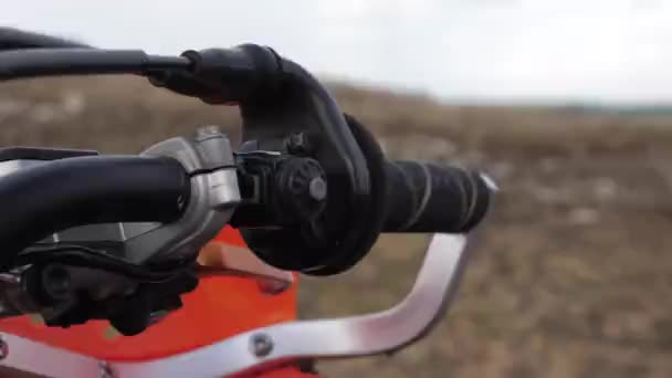 Всадник рука в черной перчатке начинает оранжевый эндуро мотоцикл — стоковое видео