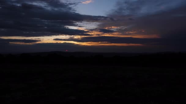 Ljusa sol uppsättningar bakom mörka täta moln i orange himmel — Stockvideo