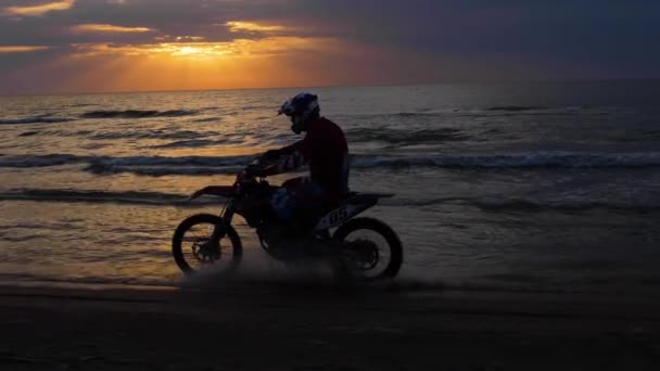 Байкерский силуэт ездит на мотоцикле против захода солнца в море — стоковое видео
