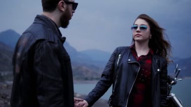sakal ve güneş gözlüğü ile yakışıklı adam bulanık dağlar ve göl karşı güzel Lady el tutar
