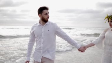 yaz elbise gülümseyen çift gri bulutlar karşı deniz kıyı şeridi boyunca yürür 