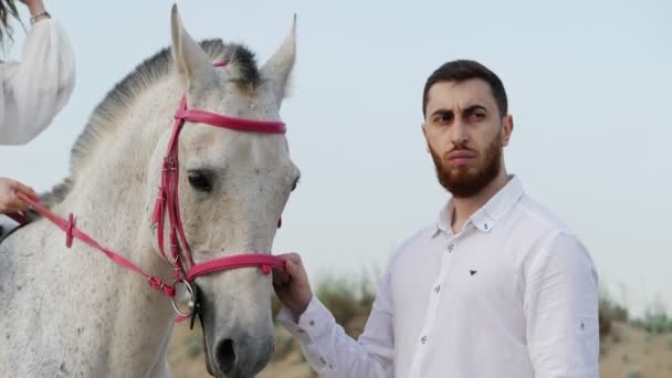 Muscoloso Uomo Barbuto Camicia Bianca Tiene Cavallo Grigio Briglia Contro — Video Stock