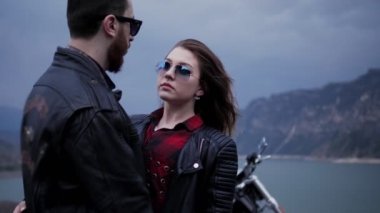 sakallı adam gece resimsel göl ve tepelere karşı Biker ceket güzel esmer sarılıyor