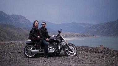 harika çift akşam tepeler arasında sakin göle karşı modern siyah ve gümüş motosiklet oturmak