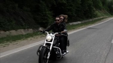 gevşek akan kıvırcık saç rüzgar ve siyah güneş gözlüğü bisiklet sürme adam sarılmak sallayarak Bayan