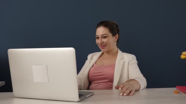 Senhora Séria Digitando Laptop Branco Sentado Mesa Madeira Contra Parede — Vídeo de Stock