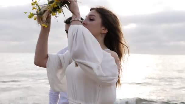 年轻女子修复松散的流动的头发 并穿上黄色花环附近的男朋友对无尽的大海 — 图库视频影像