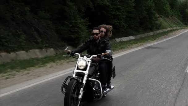 風に振ってゆるい流れる巻き毛を持つ女性とバイクに乗って黒いサングラスで男を抱きしめる — ストック動画