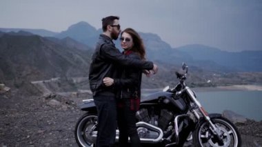 Siyah Gümüş motosiklet ve dağlar ile çevrili sakin göl karşı aşk sarılmak şık çift