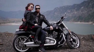 Biker çift, gece resimsel sakin göl ve kayalık tepeler karşı modern motosiklet oturuyor