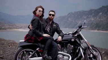 Siyah ceket yakışıklı Biker güzel Bayan gevşek akan saç ile Rüzgar Bisiklet arka koltukta oturma geceleri oturan salladı