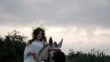 beyaz gömlek sakallı adam at üzerinde çiçek çelenk Bayan ile dizgin öfkeli gri at tutar