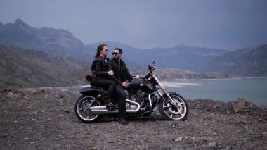 Bayan ve güneş gözlüğü sakallı adam tepeler çevrili göle karşı modern gümüş siyah motosiklet oturmak