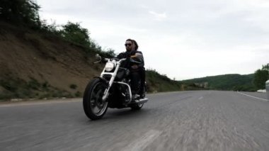 Rüzgar tarafından salladı gevşek akan saç ile güzel Bayan modern motosiklet sürme sakallı Biker tutar