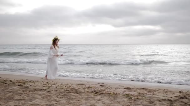 白いドレスを着た美しい裸足の女の子は ひげを生やした男に実行され 腕にジャンプし 男は砂浜で女性をねじります — ストック動画