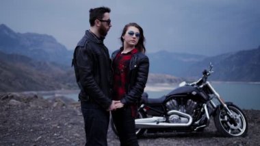 Rüzgar tarafından dalgalı gevşek akan saç ile güzel esmer motosiklet ve tepe göl karşı adam yakın standları