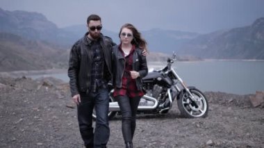mutlu şık çift kayalık tepeler arasında mavi sakin göle karşı modern motosiklet yakın yürüyor