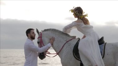 beyaz gömlek sakallı adam bulutlu gökyüzü altında sınırsız denize karşı eyer Bayan ile gri at durur