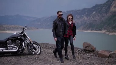 sakal ve güneş gözlüğü ile yakışıklı bisikletçinin güzel kız kucaklıyor ve Yaylası göle karşı yürüyüş