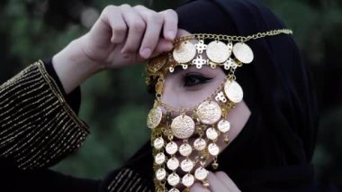 Altın kabile yüz peçe giyen kadın alnında el tutar