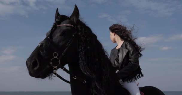 Beautiful girl rides black horse under blue sky closeup — Stock Video