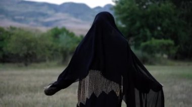 abaya elbise ve koyu peçe arap bayan glade boyunca çalışır